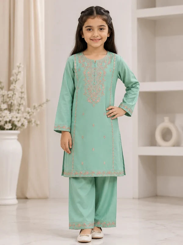 A young girl modeling a mint green traditional Indian outfit with peach embroidery, consisting of a long kurta and matching wide-leg trousers, set against a bright, modern indoor background.