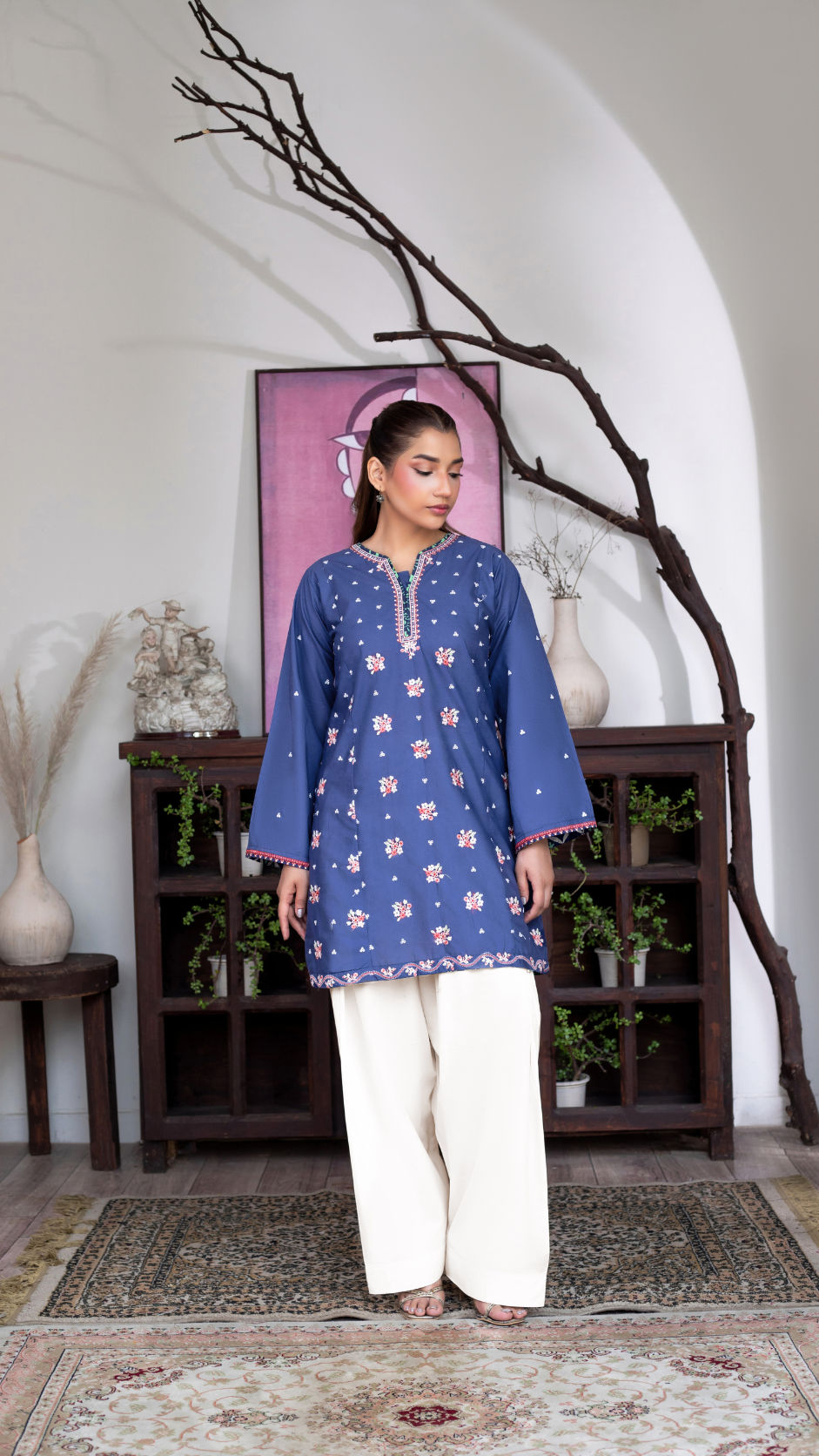 Woman wearing royal blue embroidered kurta with off-white trousers